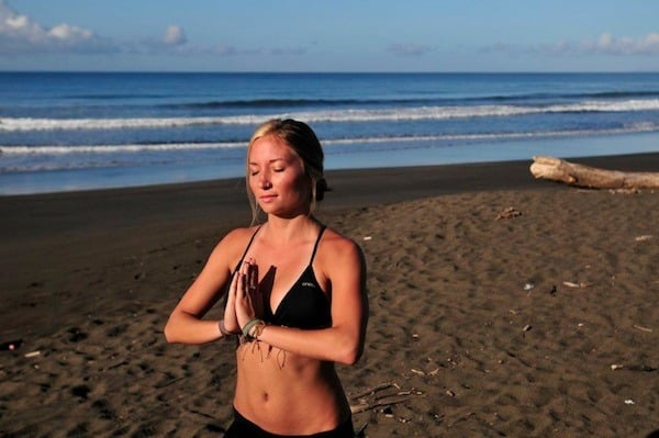 Woman doing yoga on the beach in Costa Rica at the School of the World