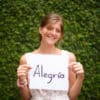 Smiling girl holding a sign that say "Alegria" which means "joy" in Spanish