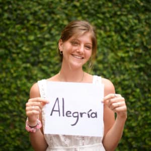 Smiling girl holding a sign that say "Alegria" which means "joy" in Spanish