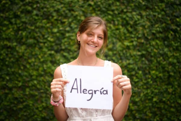 Smiling girl holding a sign that say "Alegria" which means "joy" in Spanish