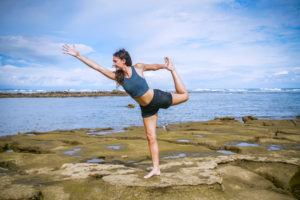 Standing bow yoga pose on the beach